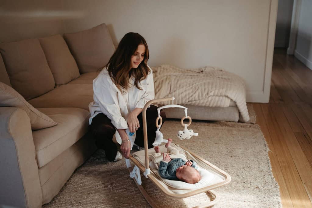a Melbourne mother sits with her newborn baby in a bouncer 