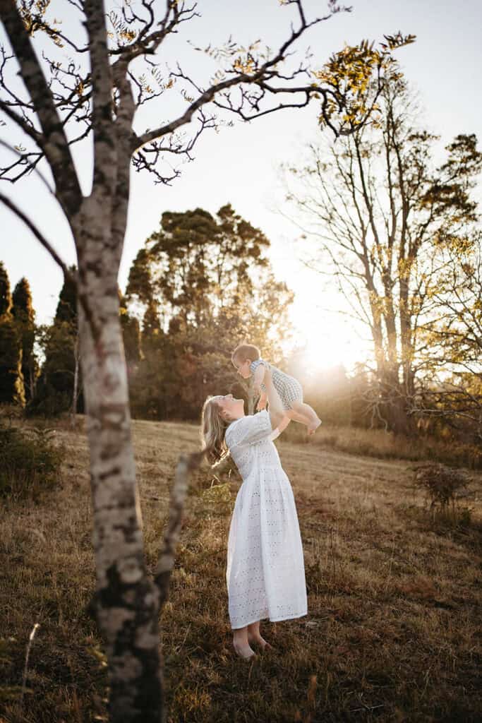 mothers day mini session mother throws baby joyfully in the air 