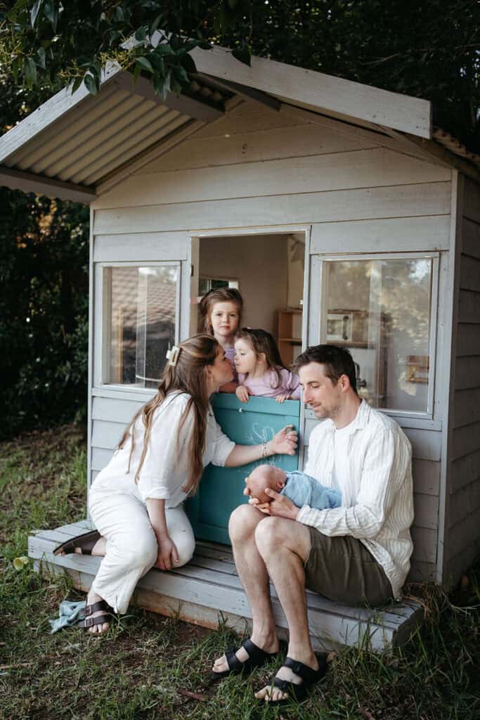 candid natural family photo of parents sitting with kids at a cubby house