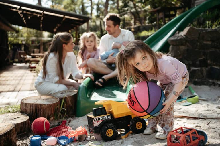 family photoshoot casual image of a young girl with a basketball infront of her family in a backyard in Melbourne