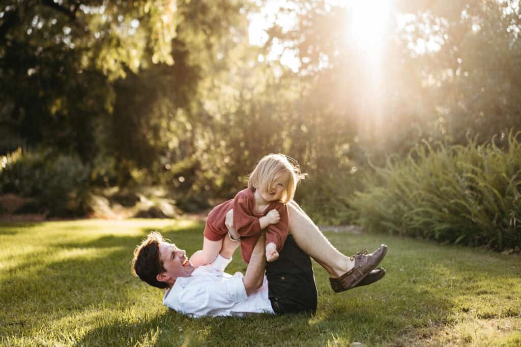 father plays with daughter on the grass at george pentland gardens in frankston